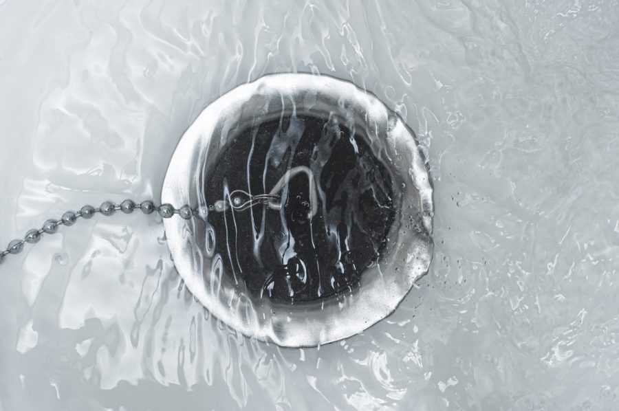 The bathroom drain is covered with a rubber plug under water.