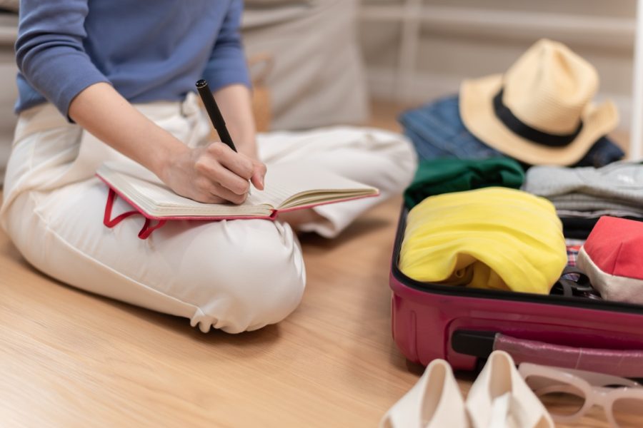 Packing a suitcase for summer travel, highlighting the vacation plumbing checklist recommended by Putman & Son’s Plumbing.