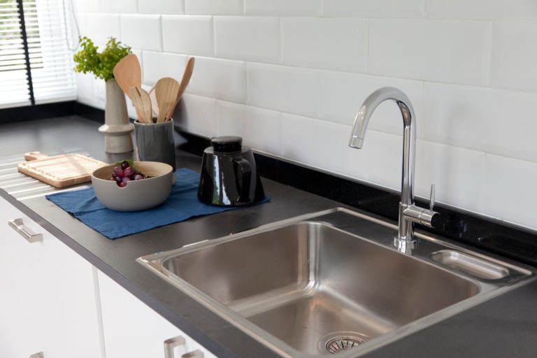 A stainless steel kitchen sink in a home, representing potential clogged sink and plumbing issues.