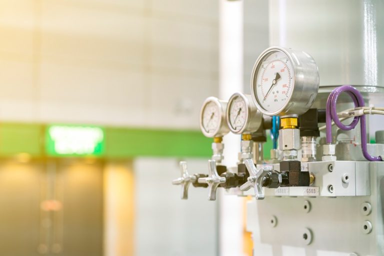 Mechanical dial pressure gauges measuring system lines, highlighting the high water pressure red flags identified by Putman & Son’s Plumbing.