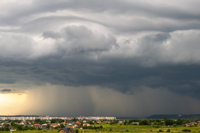 Heavy summer rainstorm clouds over residential buildings, highlighting the need for Metro Detroit sump pump maintenance.