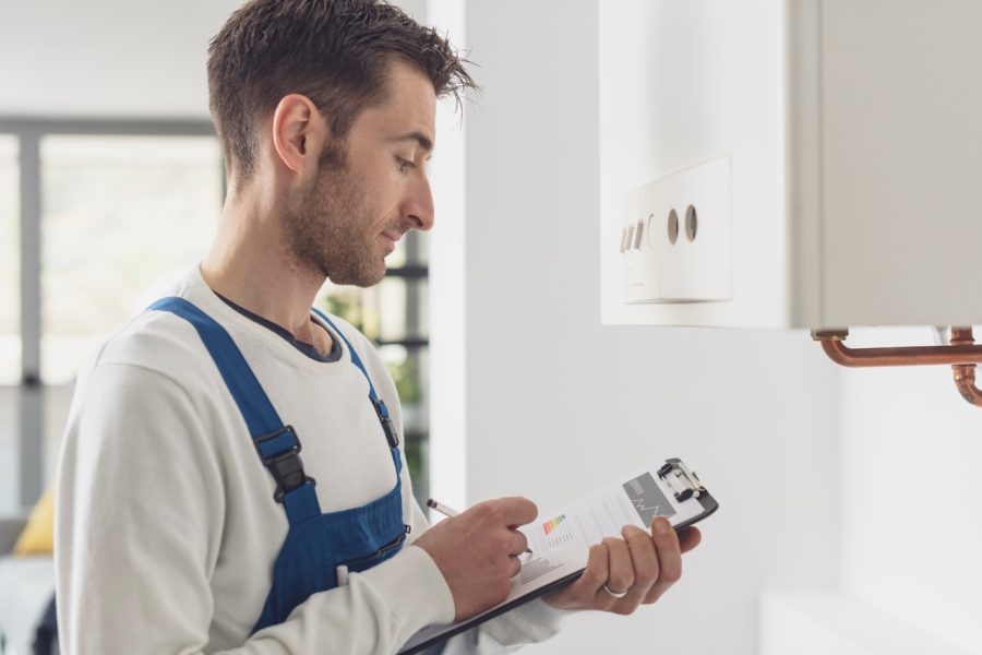 Plumbing technician inspecting home water heater and piping systems to prevent unexpected leaks.