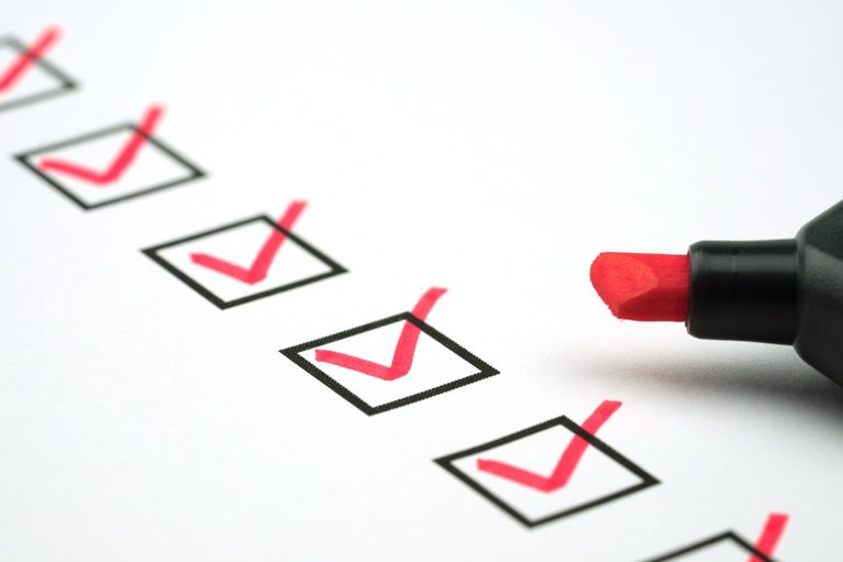 Red marker marking checkmarks on a fall plumbing maintenance checklist