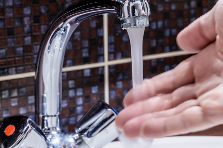 Hand testing low water flow coming from a kitchen sink faucet