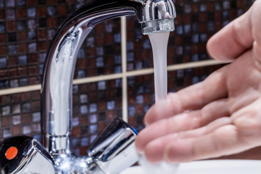 Hand testing low water flow coming from a kitchen sink faucet