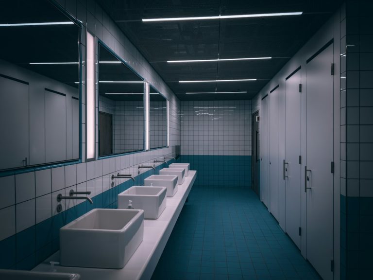 Row of sinks in a commercial restroom requiring routine plumbing maintenance
