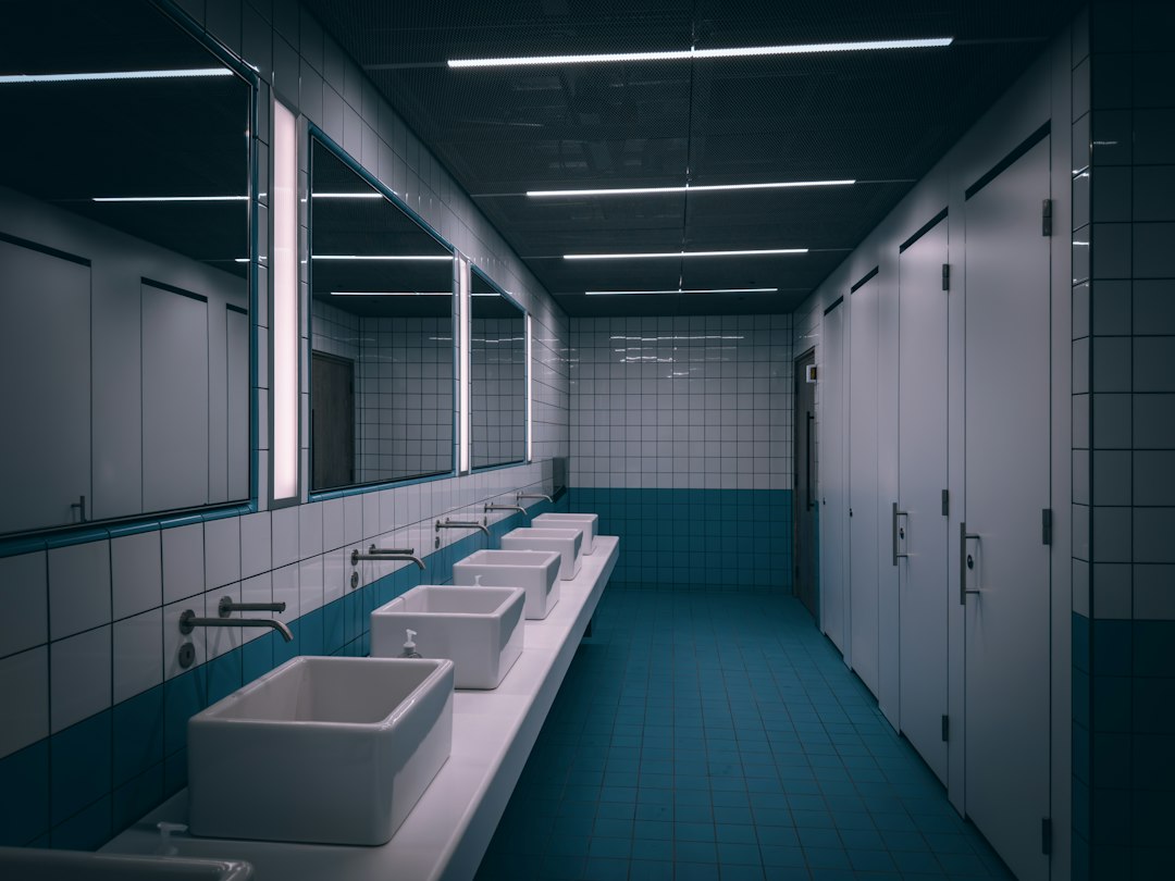 Row of sinks in a commercial restroom requiring routine plumbing maintenance
